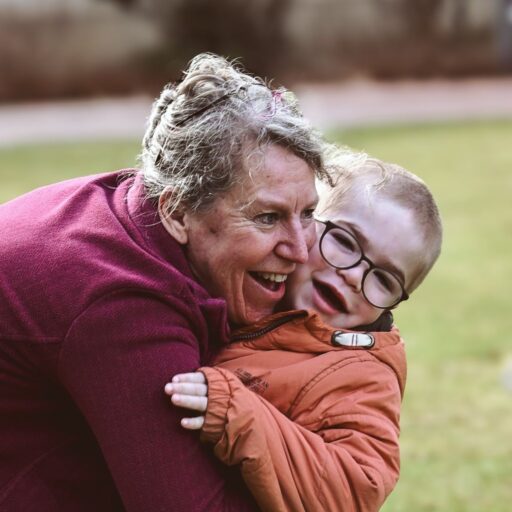 Eine Löwenherz-Pflegekraft umarmt einen kleinen Jungen, beide lachen.